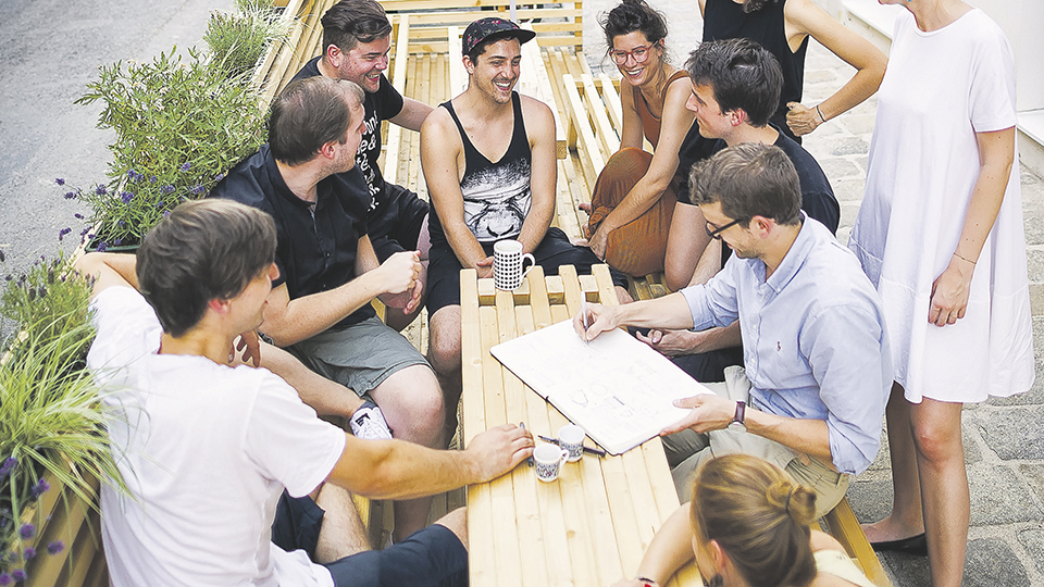 Gruppe junger menschen sitzt an einem Holztisch und unterhält sich