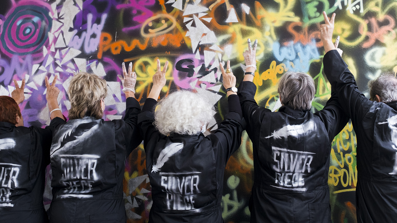 ältere Frauen bemalen eine Wand mit bunter Farbe