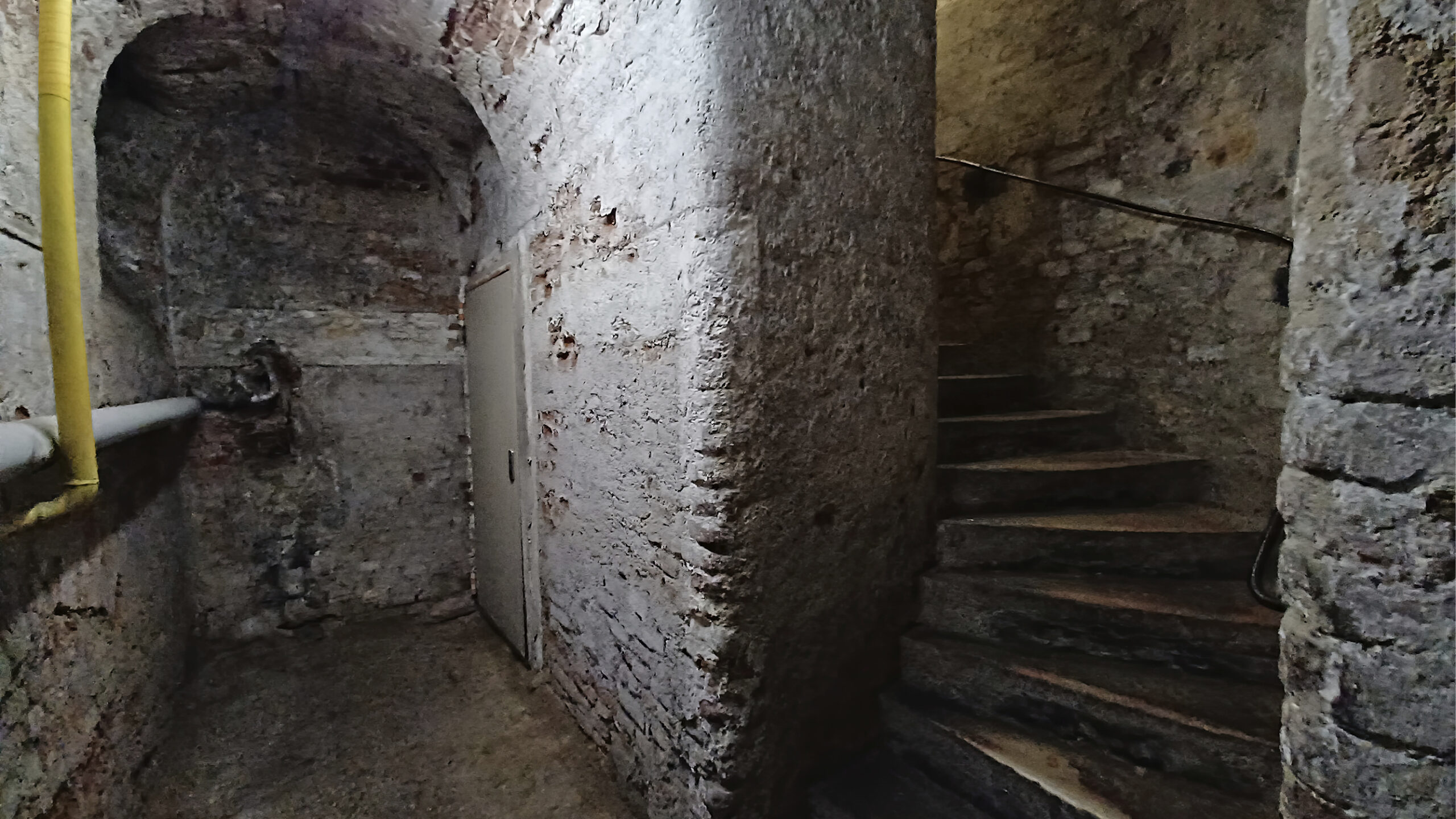 Teilbereich eines Kellers mit weiß verputzten Ziegelmauern, rechts im Bild ein Stiegenaufgang